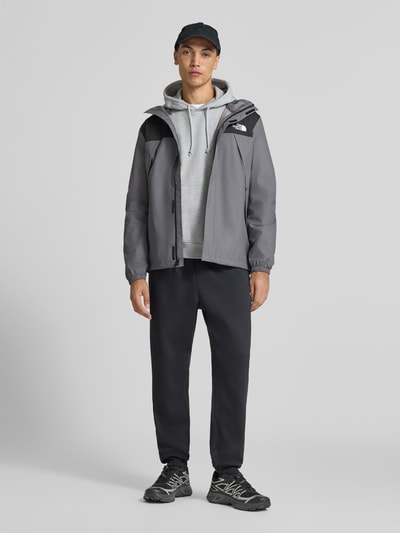 Männermodel trägt Jacke mit Label-Print Modell 'ANTORA' von The North Face in Grau mit Kapuze und Reißverschlusstaschen, Ganzkörperansicht von vorne.
