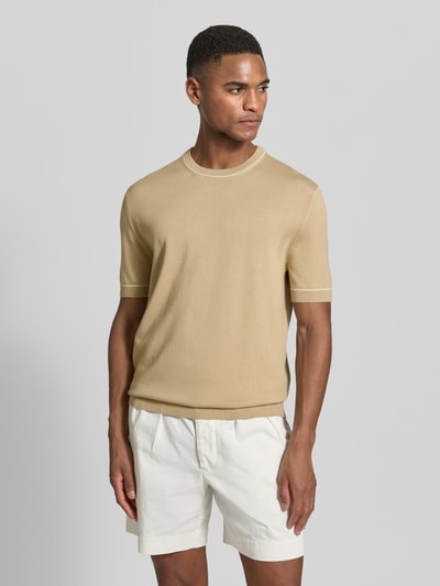 Männermodel trägt Strickshirt mit Rundhalsausschnitt von Gant in Beige, Baumwoll-Modal-Mix, gerader Schnitt, Kurzarm, Nahaufnahme Oberkörper.