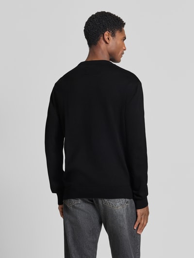 Männermodel trägt zwarte katoenen trui Regular Fit Pullover aus reiner Baumwolle model 'LOUKAA' van ARMEDANGELS, Ganzkörperansicht Rückansicht.