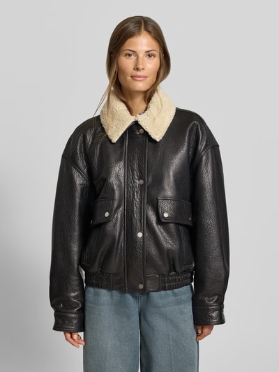 Frauenmodel trägt schwarze Regular Fit Bomberjacke mit Umlegekragen von MYON, Eingrifftaschen, elastischer Bund, Ganzkörperansicht von vorne.