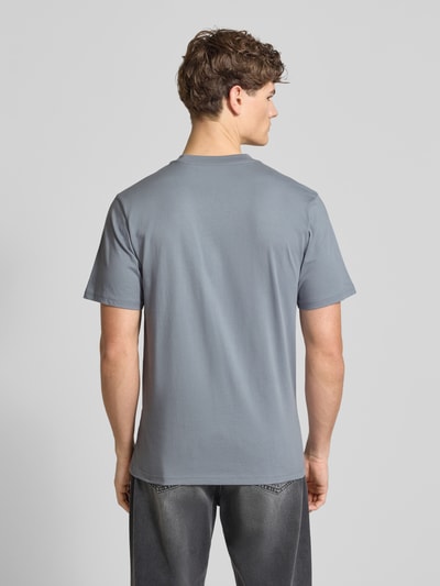 Männermodel trägt T-Shirt aus Baumwolle Modell 'Script' von Carhartt Work In Progress in Grau, gerader Schnitt, Ganzkörperansicht Rückansicht.