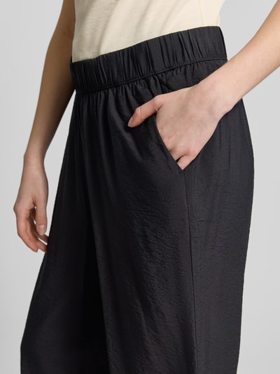 Frauenmodel trägt Loose Fit Culotte aus Viskose-Mix von s.Oliver RED LABEL in Schwarz, Popeline-Struktur, seitliche Eingrifftaschen, Nahaufnahme Oberkörper.