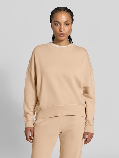 Frauenmodel trägt Oversized Sweatshirt aus Baumwoll-Mix von Juvia in Beige, gerippte Abschlüsse, Rundhalsausschnitt, Fleece-Innenseite, Ganzkörperansicht von vorne.