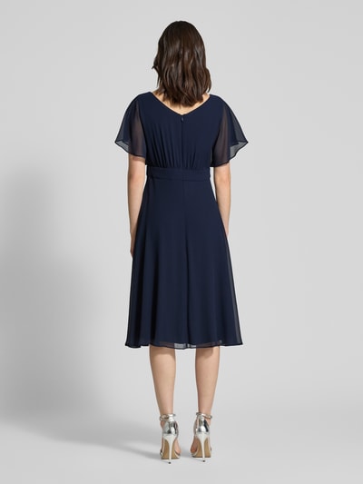 Frauenmodel trägt Knielanges Kleid mit Rundhalsausschnitt von Vera Mont, dunkelblau, semitransparent, tailliert, kurzärmelig, Rückansicht.