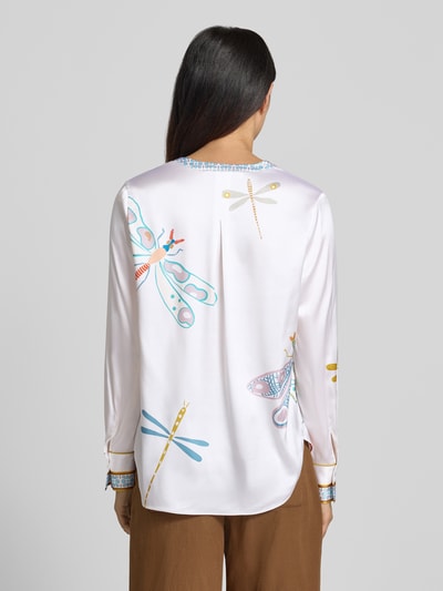 Kobiece modelka nosi Relaxed Fit Tunika-Bluse mit Allover-Motiv-Print od HERZENS, dekolt z lamówką, krój relaxed fit, nadruk z motywem na całej powierzchni, tył wydłużony, z długim rękawem, długość tyłu w rozmiarze 36: 68 cm, długość rękawów w rozmiarze 36: 63 cm, jasne pastelowe kolory, wzory ważek, gładka tekstura, widok całej sylwetki z tyłu.