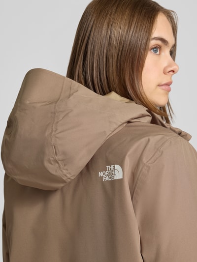 Frauenmodel trägt Regular Fit Funktionsjacke mit Logo-Print Modell 'Quest Mono' von The North Face, beige, glatte Struktur, Nahaufnahme Oberkörper. Damen Funktionsjacke, Kapuze, Reißverschluss, Rückenlänge 69 cm, Schulterbreite 40 cm, Brustweite 40 cm, Ärmellänge 63 cm.