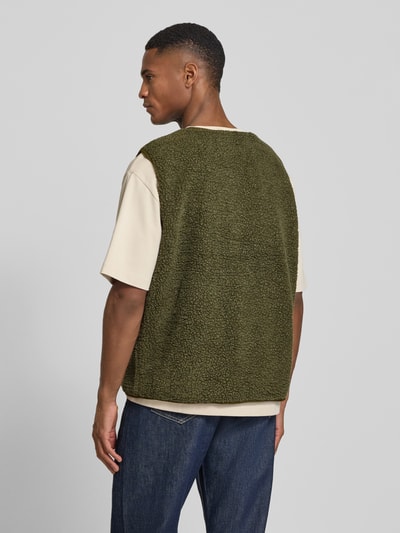 Männermodel trägt Straight Fit Weste mit Logo-Patch Modell 'Hoktown' von American Vintage, Kunstfell in Olivgrün, Ganzkörperansicht Rückansicht.