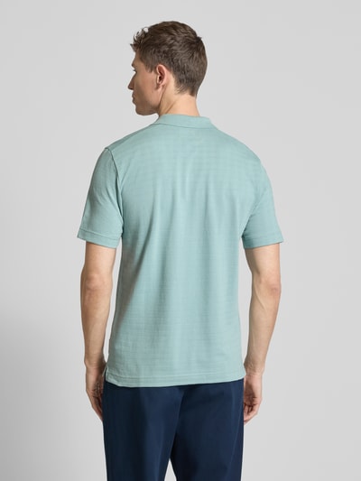 Männermodel trägt Regular Fit Poloshirt aus reiner Baumwolle von Marc O'Polo, unifarben, Gitterkaro Struktur, Ganzkörperansicht Rückansicht.