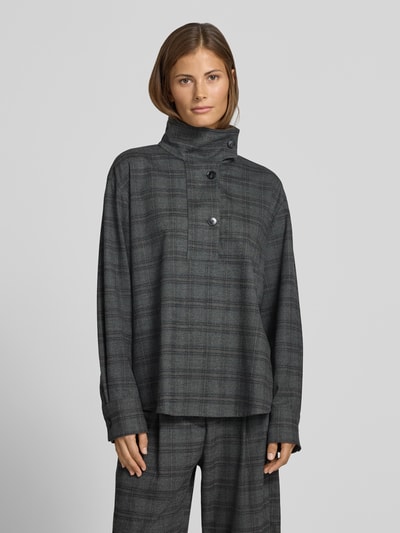 Frauenmodel trägt Bluse mit Stehkragen und kurzer Knopfleiste von Style Icon Collection, grau kariert mit abgerundetem Saum, Ganzkörperansicht von vorne.