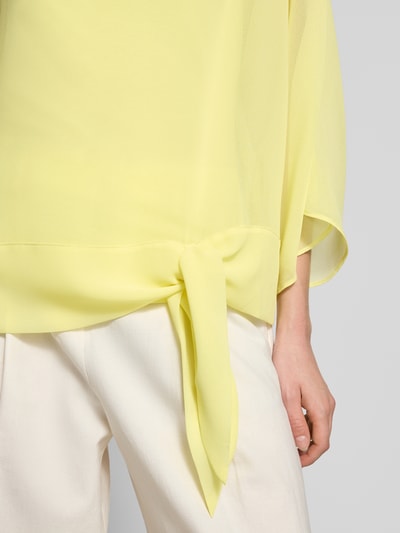 Frauenmodel trägt Relaxed Fit Bluse in semitransparentem Design von Betty Barclay, Zierschleife, gelb, Nahaufnahme Oberkörper. Damen Bluse, Rundhalsausschnitt, Langärmelig, Rückenlänge 57 cm, Ärmellänge 45 cm.