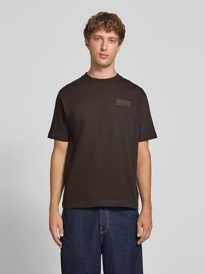 Männermodel trägt Relaxed Fit T-Shirt aus reiner Baumwolle von Marc O'Polo DENIM in Dunkelbraun, lockere Passform, Ganzkörperansicht von vorne.