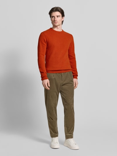 Męski model nosi Oversized Strickpullover mit gerippten Abschlüssen von Casual Friday, lanawoll-mix, okrągły dekolt, długie rękawy, oliwkowe spodnie, białe buty, pełny widok z przodu.