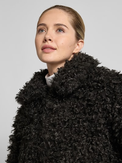 Frauenmodel trägt Felljacke in cropped-Fit – curated by Isabelle Hartmann von Style Icon Collection, schwarzes Kunstfell mit Reißverschluss, Nahaufnahme Oberkörper.