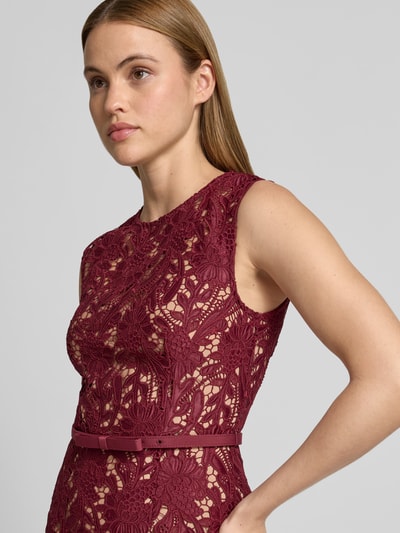 Vrouwenmodel draagt Maxikleid aus floraler Spitze van Self-Portrait in bordeaux, elastische materiaalmix, slim fit, afneembare tailleband, mouwloos design. Nahaufnahme bovenlichaam.
