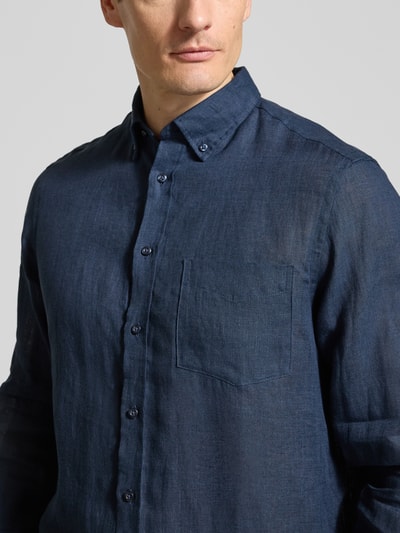 Mężczyzna nosi Slim Fit Leinenhemd mit Brusttasche od Christian Berg Men, ciemnoniebieski len, kołnierzyk typu button down, listwa guzikowa, brystasza, krój slim fit, długość tyłu w rozmiarze M: 79 cm, szerokość w rozmiarze M: 43 cm, długość rękawów w rozmiarze M: 68 cm, zbliżenie na górną część sylwetki