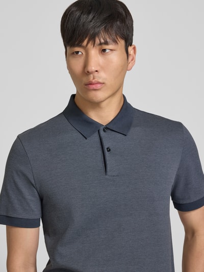 Męski model nosi Regular Fit Poloshirt aus reiner Baumwolle Modell 'H-PARLAY 102' od BOSS, bi-colour, kołnierzyk polo, krótki rękaw, bawełna, zapięcie na krótką listwę guzikową, wykończenie z rozcięciami po bokach, widok na górną część ciała z przodu.