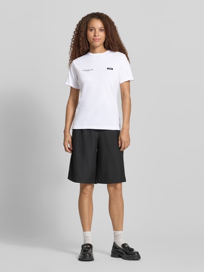 Modelka nosi T-Shirt mit Logo-Print und Label-Patch od Karo Kauer, czysta bawełna, krój straight fit, okrągły dekolt, długość tyłu w rozmiarze S: 62 cm, przód cała sylwetka