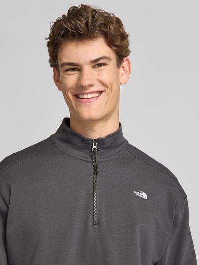 Mannelijk model draagt Relaxed Fit Sweatshirt met Stehkragen en Reißverschluss van The North Face in antraciet, katoen, label-stitching, detailopname bovenlichaam.