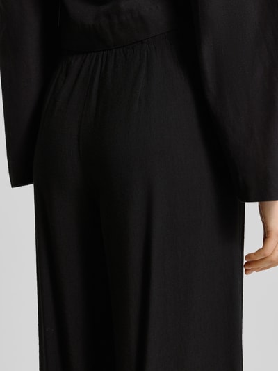 Frauenmodel trägt Wide Fit Stoffhose aus Viskose-Mix Modell 'Frencis' von STEHMANN in Schwarz mit elastischem Bund, Nahaufnahme Rückansicht.