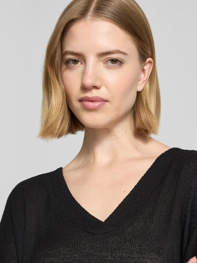 Frauenmodel trägt Strickshirt mit V-Ausschnitt Modell 'Delia' von Soyaconcept, schwarzer Viskose-Mix mit Stretch-Anteil, Nahaufnahme Oberkörper.