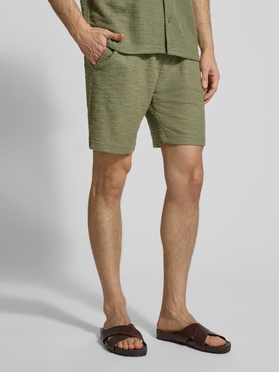 Männermodel trägt Shorts mit elastischem Bund von MCNEAL in Grün mit Strukturmuster aus Material-Mix, Regular-Fit, Nahaufnahme Unterkörper.