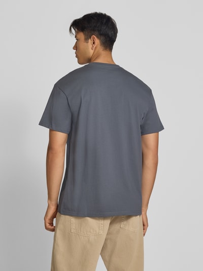 Männermodel trägt T-Shirt mit Label-Stitching und Rundhalsausschnitt von Carhartt Work In Progress, Baumwolle, Regular Fit, Ganzkörperansicht Rückansicht.