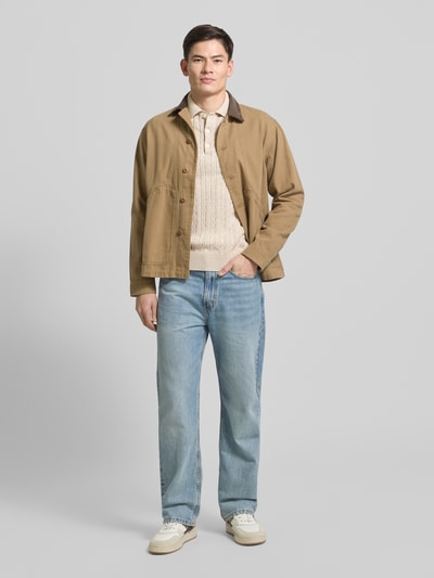 Männermodel trägt Regular Fit Strickpullover aus reiner Baumwolle von Tommy Hilfiger, Optik: Unifarben, Zopfmuster, Logo-Applikation, Polokragen, Langarm, gerippter Ärmelabschluss und Rumpfabschluss, Materialverarbeitung: Strick, Ganzkörperansicht von vorne.