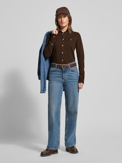 Kobiece modelka nosi Bluzka koszulowa mit Label-Stitching von Polo Ralph Lauren, bawełna, krój slim fit, kołnierzyk typu button down, listwa guzikowa, brązowy kolor, proste kształty, gładka tekstura, długość tyłu 67 cm, długość rękawów 64 cm w rozmiarze S, całkowity widok z przodu.