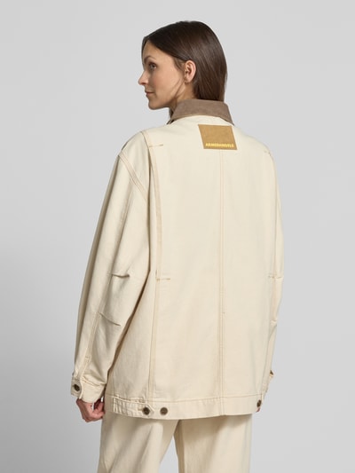 Frauenmodel trägt Oversized Jeansjacke aus reiner Baumwolle Modell 'WORKWEAR CANVAS' von Armedangels in Beige, Detailnähte, Label Patch, Rückansicht Ganzkörperansicht.