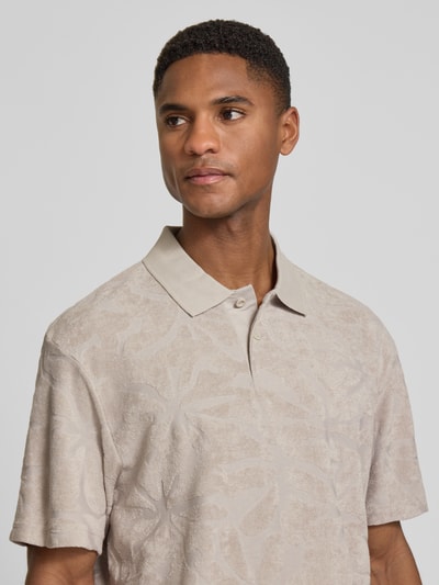 Männermodel trägt Regular Fit Poloshirt aus Baumwoll-Mix Modell 'PE_FLOWER' von BOSS Orange, Optik:Allover-Muster, Struktur-Muster, Label-Applikation, Polokragen, V-Ausschnitt, 2-Knopf-Verschluss, Kurzarm, Rumpfabschluss mit Seitenschlitzen, Materialverarbeitung: Frottee; Nahaufnahme Oberkörper.