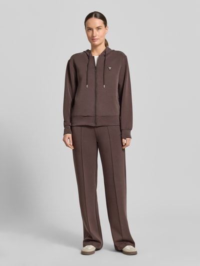 Frauenmodel trägt Sweatjacke mit Kapuze Modell 'OLYMPE' von Guess Activewear in Braun im Material-Mix mit Modal-Anteil und Label-Applikation, Regular-Fit, Reißverschluss, Ganzkörperansicht von vorne.