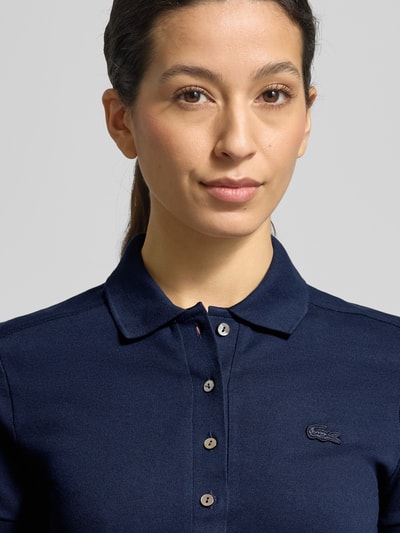 Frauenmodel trägt Regular Fit Poloshirt aus Baumwoll-Mix von Lacoste Sport in Dunkelblau, unifarben, Logo-Stitching, Nahaufnahme Oberkörper.