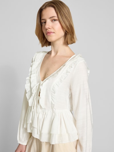 Frauenmodel trägt Regular Fit Langarmbluse aus Viskose-Mix Modell 'ZOEY' von Vero Moda, unifarben mit Flounce-Detail, Nahaufnahme Oberkörper.