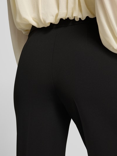 Frauenmodel trägt schwarze Stoffhose mit Bundfalten von Stehmann, glatte Struktur, unifarben, Detailaufnahme Rückenansicht.