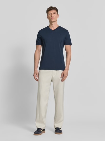 Męski model nosi Regular Fit T-Shirt aus reiner Baumwolle von s.Oliver RED LABEL, jednolity kolor, aplikacja z metką, dekolt w serek, krótki rękaw, dżersej, bawełna, zdjęcie całej sylwetki z przodu.