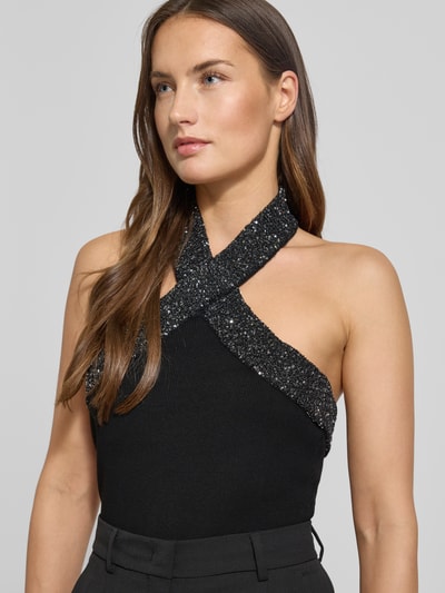 Frauenmodel trägt Blusentop mit Neckholder von Mango aus schwarzem Viskose-Mix mit Paillettenbesatz, Slim Fit, Nahaufnahme Oberkörper. Rückenlänge bei Größe S: 30 cm.
