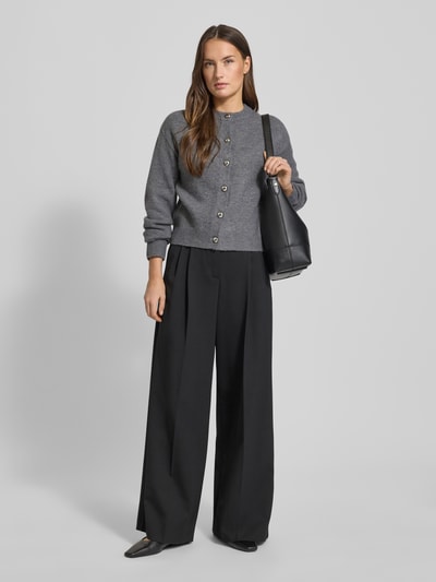 Frauenmodel trägt Cardigan mit Rundhalsausschnitt Modell 'FELIPE' von Mango im Material-Mix mit Woll-Anteil, gerader Schnitt, Knopfverschluss, Rückenlänge 52 cm, Ärmellänge 58 cm, oversize schwarze Hose, Farben Grau und Schwarz, strukturierte Maschenoptik, Ganzkörperansicht von vorne.