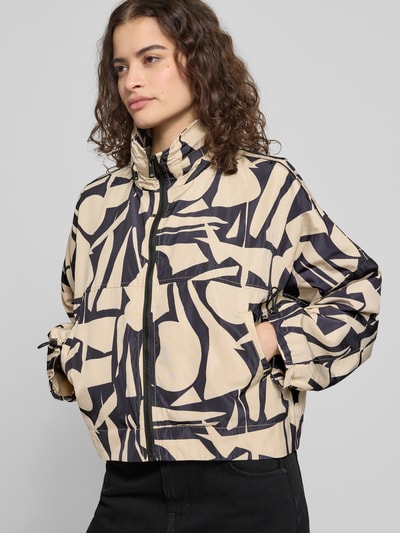 Modelka nosi Oversized Hemdjacke mit Allover-Muster Modell 'BETTY BATSLEEVE' von ONLY, efekt: wzór na całej powierzchni, krój oversized, stójka z chowaną kapturem, zamek błyskawiczny, graficzny wzór, długość krótka, rękawy nietoperzowe, elastyczne zakończenia rękawów, wpuszczane kieszenie boczne, widok całego ciała z przodu.