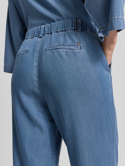 Vrouwenmodel draagt Straight Fit broek uit lyocellmix met viscose van MOS MOSH, model 'Bai Lich', mediumblauw, detailopname achterkant. Context: dames broek van MOS MOSH, lyocellmix met viscose, straight fit, model 'Bai Lich', knoop- en ritssluiting, bandwijdte maat 36: 39 cm, binnenbeenlengte maat 36: 79 cm.