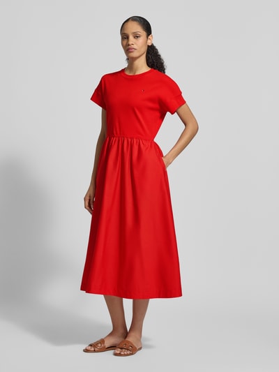 Vrouwenmodel draagt Ausgestelltes Freizeitkleid aus Material-Mix Modell 'CODY' van Tommy Hilfiger in effen rood, midi-lengte, ronde hals, korte mouwen, katoen-mix materiaal, logo-stiksel, zonder sluiting, a-lijn fit, frontale volledige lichaamsweergave.
