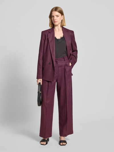 Frauenmodel trägt Straight Fit Leinenhose mit Bügelfalten Modell 'Tempoli' von Mango in dunklem Lila, reine Leinen, Ganzkörperansicht von vorne.
