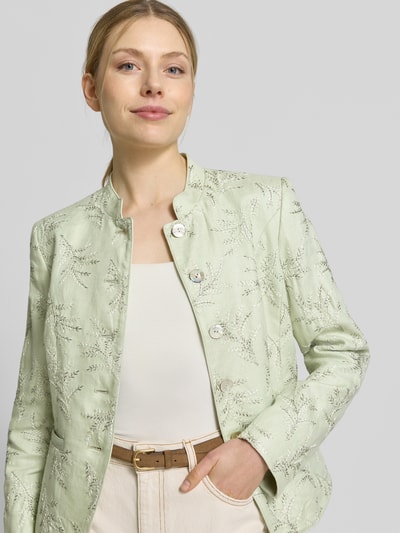 Kobieta modelka nosi Slim Fit Blazer mit Stitchings und Stehkragen von WHITE LABEL w jasnozielonym kolorze z delikatną teksturą, krój slim fit, stójka, dekoracyjne przeszycia, kieszenie wsuwane, długość tyłu w rozmiarze 36: 59 cm, szerokość w rozmiarze 36: 47 cm, długość rękawa w rozmiarze 36: 65 cm, zbliżenie na górną część ciała z przodu.