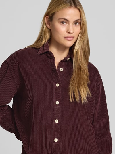 Frauenmodel trägt Oversized Hemdbluse aus reiner Baumwolle Modell 'Padow' von American Vintage, Cord-Optik, dunkelrot, Nahaufnahme Oberkörper.