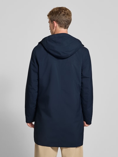 Männermodel trägt Regular Fit Mantel mit Kapuze Modell 'Brussel' von Helly Hansen in Dunkelblau, Rückansicht, Ganzkörperansicht von hinten. Herren Mantel, Logo-Detail, Rückenlänge 96 cm, Schulterbreite 46 cm, Brustweite 51 cm, Ärmellänge 66 cm.