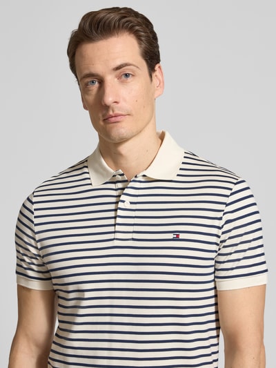 Mannmodel draagt Regular Fit Poloshirt uit zuivere katoen model 'LIQUID COTTON' van Tommy Hilfiger met melangelook en logo-stitching, polokraag, korte mouwen met geribde zoom, zijsplitten, Nahaufnahme bovenlichaam.