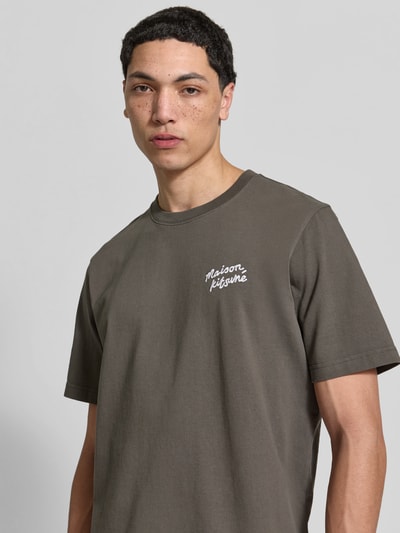 Männermodel trägt Regular Fit T-Shirt aus reiner Baumwolle von MAISON KITSUNÉ in Olive mit Label-Stitching, Nahaufnahme Oberkörper.