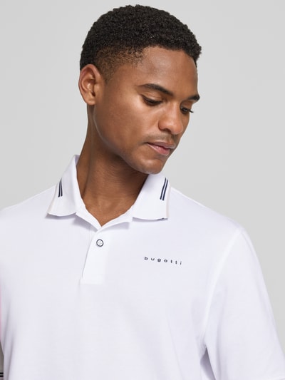 Männermodel trägt Regular Fit Poloshirt mit Logo von bugatti, weiß mit Knopfleiste, Baumwoll-Mix mit Stretch, Nahaufnahme Oberkörper.