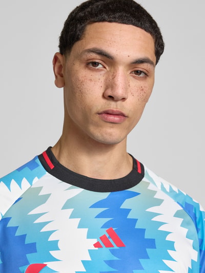 Männermodel trägt Regular Fit T-Shirt mit Allover-Muster von adidas Sportswear, Label-Print, Rundhals, Kurzarm, Nahaufnahme Oberkörper.