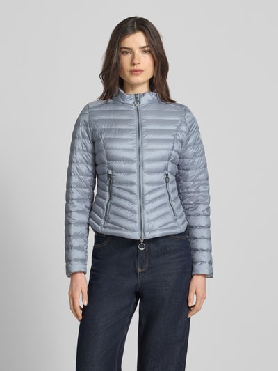 Frauenmodel trägt Steppjacke mit Stehkragen von Gil Bret in Silber, Zweiwege-Reißverschluss, Reißverschlusstaschen, Körpernahe Passform, Rückenlänge 56 cm, Schulterbreite 39 cm, Brustweite 47 cm, Ärmellänge 66 cm, Ganzkörperansicht von vorne.