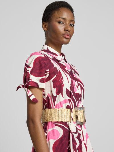 Frauenmodel trägt Hemdblusenkleid mit Gürtel Modell 'Ta44mara' von ZABAIONE, Allover-Muster in Weiß, Pink und Weinrot, Nahaufnahme Oberkörper.